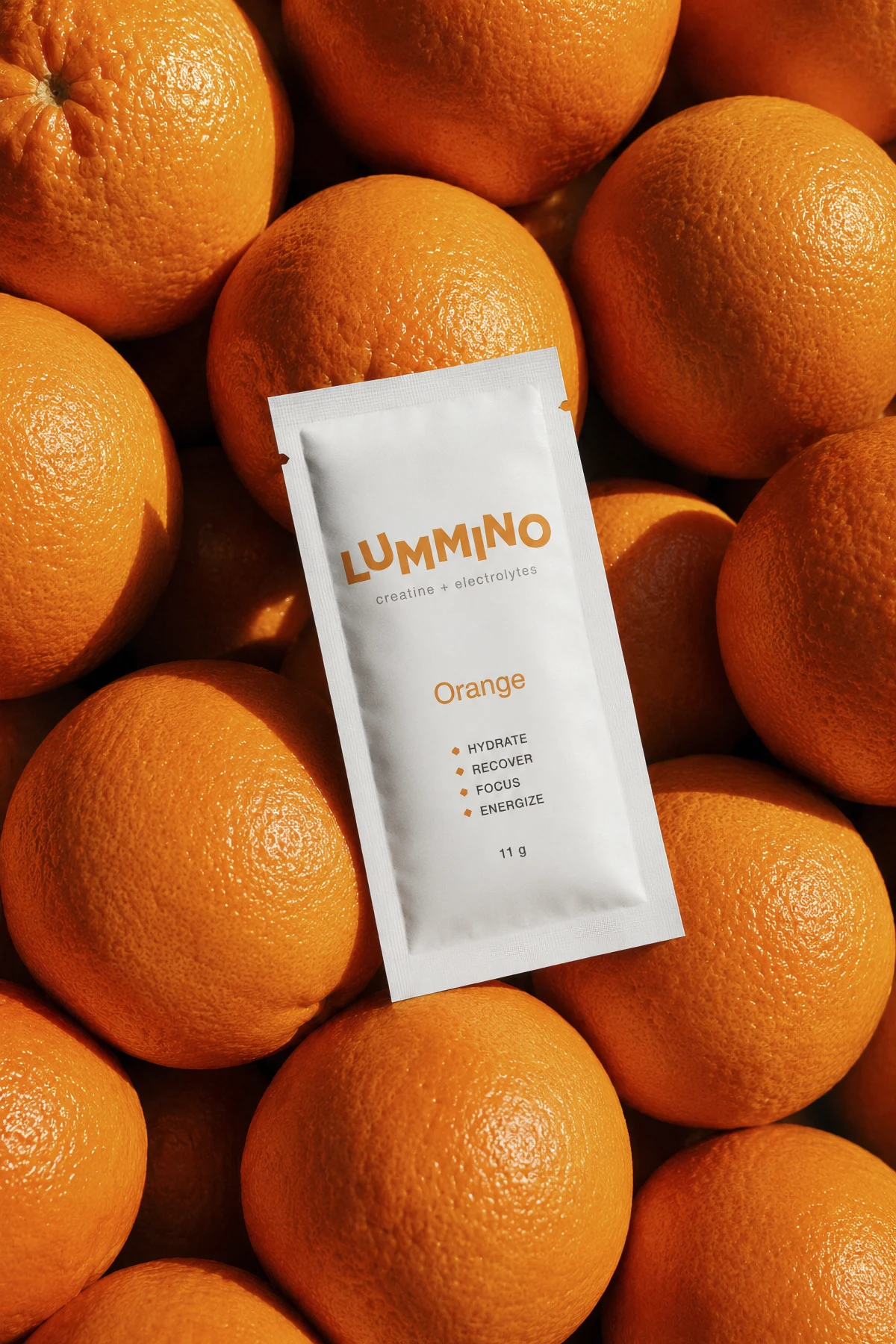 A Lummino orange sachet resting on a bed of fresh oranges